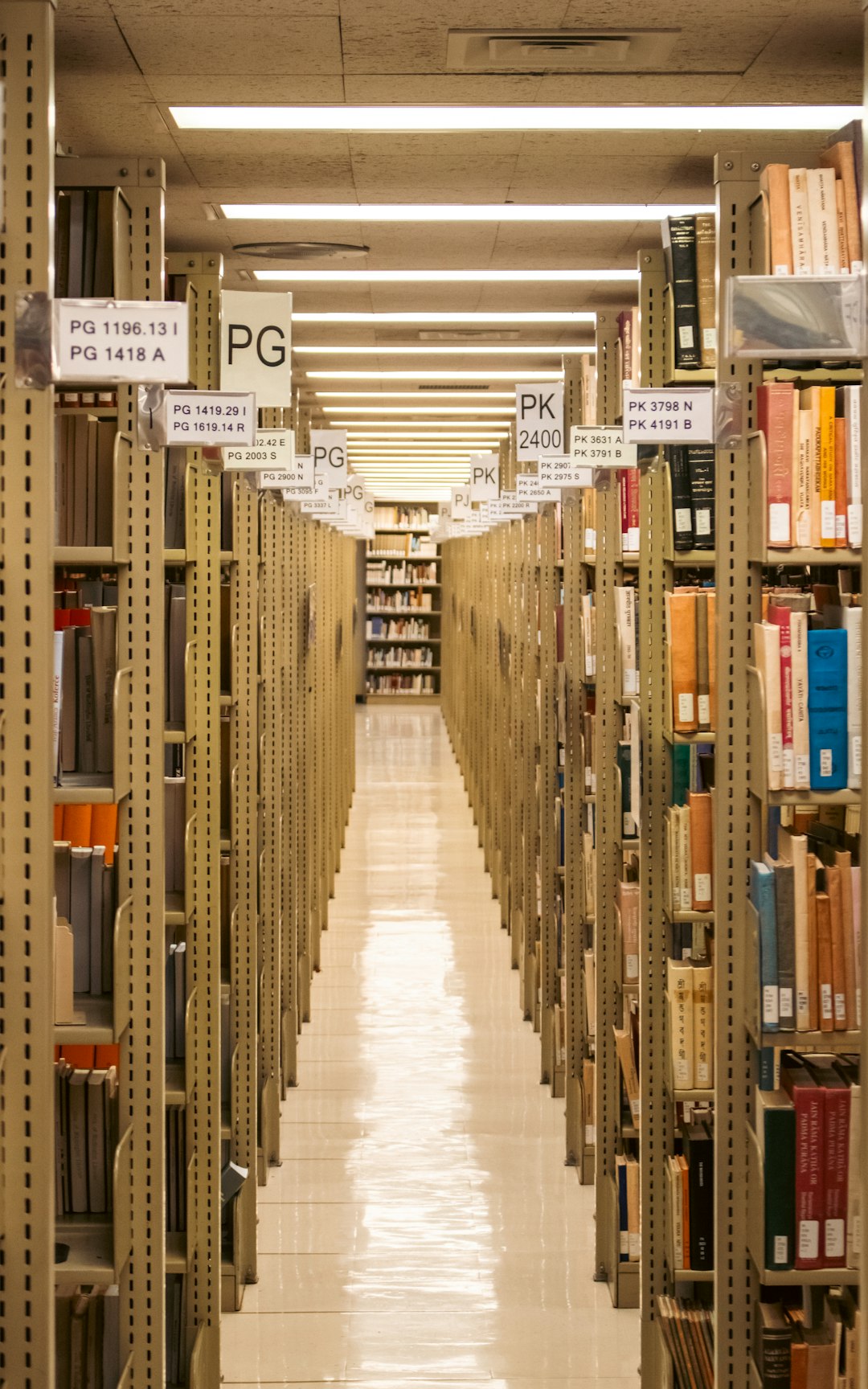 A long aisle between tall bookshelves in the Suzzallo and Allen Libraries at the University of Washington in Seattle, USA.